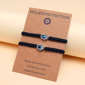 Détail de deux bracelets tressés main de Fatma avec œil bleu sur une carte de présentation