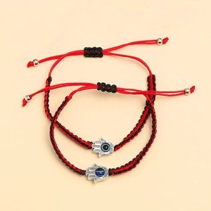 Détails de la main de fatma et de l'oeil maléfique sur bracelets tressés rouge et noir