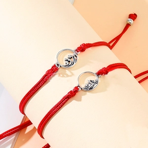 Detailansicht der roten geflochtenen Pärchen-Armbänder mit Berg- und Wellenanhänger