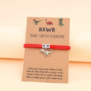 Detail of red woven dinosaur bracelet with heart bead on a gift card with a poem