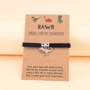 Detail of woven dinosaur charm bracelet on gift card with heart beads and black cord