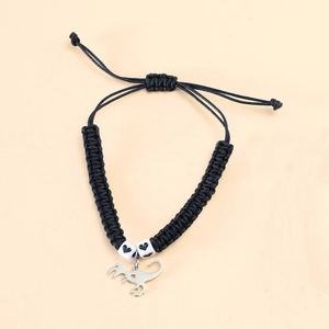Close-up of a handmade dinosaur charm bracelet with heart beads and woven black cord