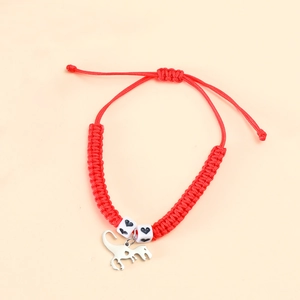Detail of red woven bracelet featuring a silver dinosaur charm and white heart beads