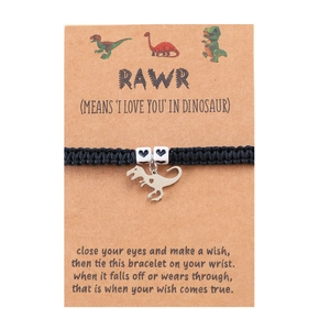 Close-up of handmade woven dinosaur bracelet with heart beads and silver T-Rex charm on card