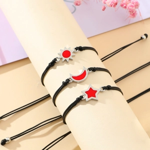 Three-piece sun moon and star woven bracelets with red enamel charms and adjustable cords