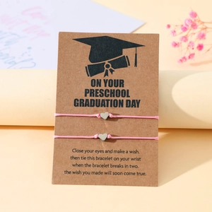 Dettaglio di braccialetti intrecciati rosa con ciondoli a cuore su biglietti di laurea
