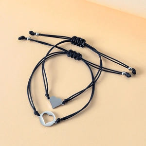 Detail view of woven couple bracelets featuring solid heart and hollow circle charms