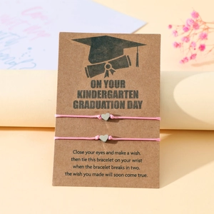 Dettaglio di braccialetti a cuore intrecciati rosa su biglietto regalo di laurea