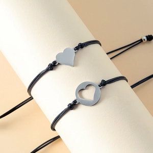 Detail view of handmade woven cord bracelets with complementary metal heart pendants