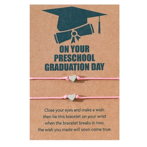 Braccialetti graduazione intrecciati rosa con ciondoli a cuore su cartolina