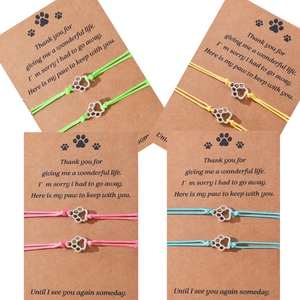 Detail showing four colorful woven paw print charm bracelets on memorial gift cards