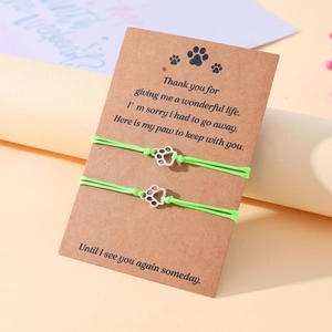 Close-up of neon green woven pet paw charm bracelets on a sentimental gift card