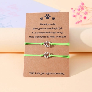 Close-up of neon green braided paw print bracelets on a kraft memorial greeting card.