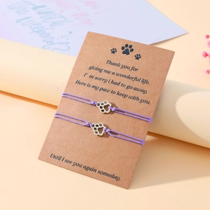 Macro detail of two purple braided cat paw bracelets on a memorial gift card
