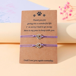 Detail of purple woven pet memorial bracelets with silver paw print charms on card