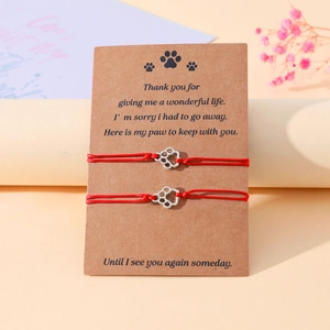 Detail of red woven pet memorial bracelets with silver paw charms on kraft card