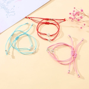 Detail of colorful hand-woven bracelets featuring hollow dog paw charms and adjustable cords
