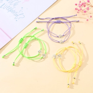 Detail of handmade woven bracelets with silver paw charms in purple, green, and yellow
