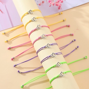Macro detail of colorful woven friendship bracelets with silver metal cat paw charms