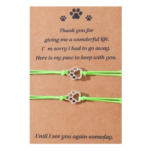 Close-up of handmade woven paw print charm bracelets on a pet memorial card
