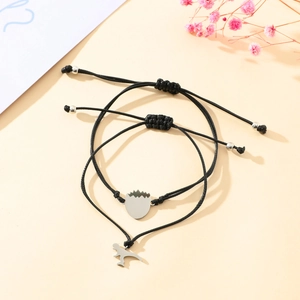 Detail of adjustable black woven bracelets featuring dinosaur and hatching egg charms