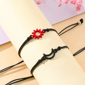 Detail of adjustable sun and moon braided rope bracelets on a cream cylinder display