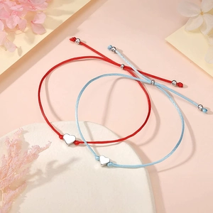 Nahaufnahme minimalistischer gewebter Armbänder mit Herzanhängern auf einer Geschenkkarte