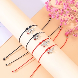 Detail of four woven dinosaur heart bracelets on a beige display stand with flowers