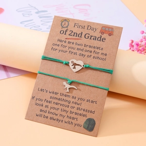 Detail of two dinosaur heart bracelets on a First Day of 2nd Grade gift card