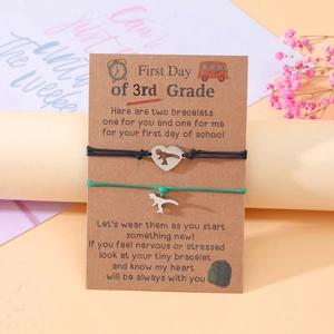 Detail showing two handmade cord bracelets with dinosaur charms on a 3rd Grade school card