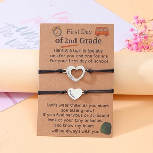Close-up of mother and daughter braided bracelets with heart charms on card