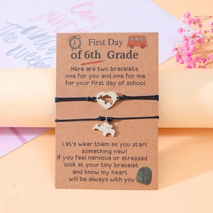 Detail of two handmade black string bracelets with heart and elephant charms for school