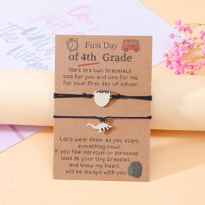 Close-up of 4th Grade school bracelets with dinosaur pendants on a message card