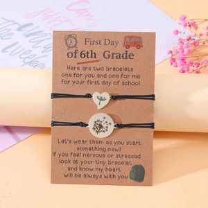 Macro shot of 6th grade woven bracelets with dandelion charm on themed display card