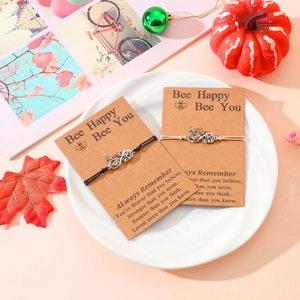 Detail of infinity sister bracelets with bee charms on a brown gift display card