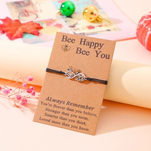 Handmade infinity friendship bracelet with gold bees on a decorative gift card