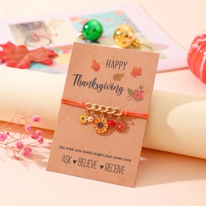 Detalle de girasol y colgantes florales en una pulsera tejida naranja de Acción de Gracias