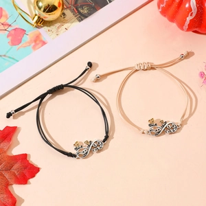 Detail of woven infinity bracelets with sister engraving and a bee charm in autumn setting
