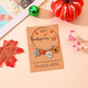 Detail of silver bangle with tree of life and sunflower charms on a Thanksgiving card