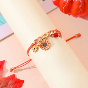 Detalle de pulsera de girasol con cordón naranja, decoración de calabaza y hoja de arce