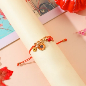 Detalle de pulsera tejida roja con dijes de girasol y acentos de cadena dorada