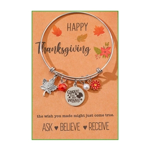 Detail of silver Thanksgiving bracelet with turkey charm and maple leaf pendant on card