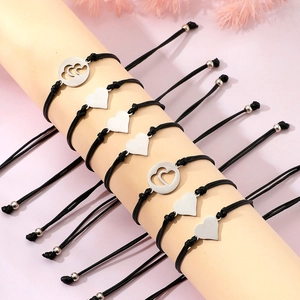 Detail von verstellbaren schwarzen Herz-Armbändern mit polierten Silberanhängern