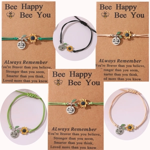 Detailed view of bee sunflower woven bracelets with Bee Happy engraved charms on cards