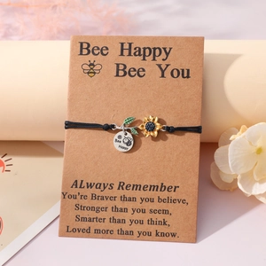 Detail of Bee Happy engraved charm and sunflower pendant on black cord bracelet