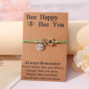 Detail of sunflower and bee charm on a green braided cord bracelet with card