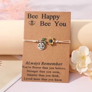 Detailed view of woven sunflower bracelet with Bee Happy charm on a gift card packaging