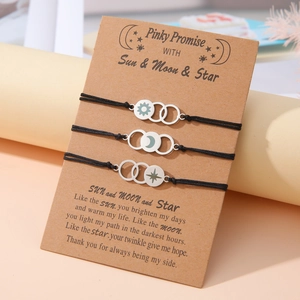 Detail of sun moon star charms on woven cords displayed on a kraft paper gift card