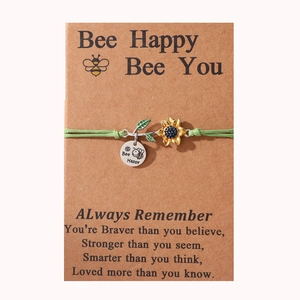 Detail of green braided bracelet with sunflower pendant and Bee Happy charm on card