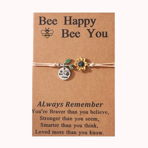 Detail of bee and sunflower charms on a braided bracelet with a gift backing card